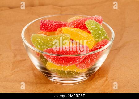 Plusieurs sucreries de marmelade sucrées dans une plaque de verre sur papier kraft, macro. Banque D'Images