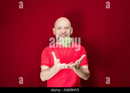 Un homme lance une pomme de sucre sur fond rouge Banque D'Images