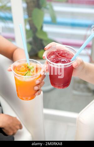 Deux filles tenant des pinceaux surgelés à la pêche et à la fraise dans des tasses en plastique. Banque D'Images