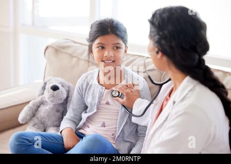 Médecin examinant une petite fille avec stéthoscope. Pédiatre féminin écoutant les battements de cœur des enfants lors d'une visite à domicile ou d'un examen à la clinique. Attention Banque D'Images