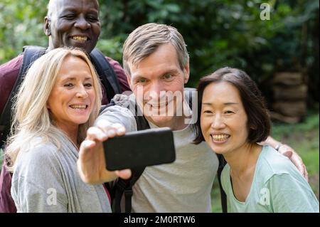 Amusant groupe diversifié d'amis d'âge moyen prenant un selfie dans le parc public Banque D'Images