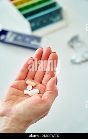 La main d'une femme âgée tenant un tas de pilules Banque D'Images