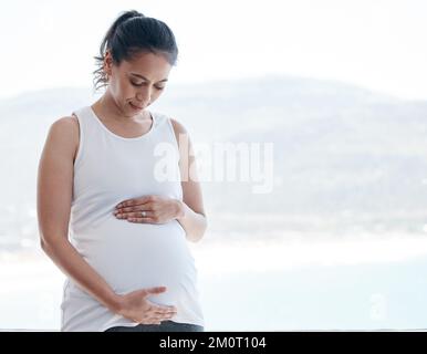 Déjà tout. une femme enceinte se frottant le ventre à la maison. Banque D'Images