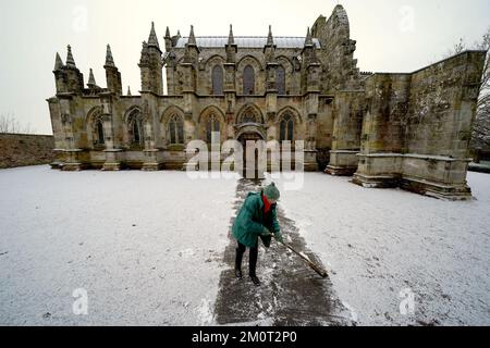 Une personne se dégage de la voie de la chapelle Rosslyn à Edingburgh après une légère poussière de neige. Date de la photo: Jeudi 8 décembre 2022. Banque D'Images