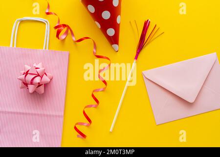 Vue de dessus de la tête de fête près du sac et de l'enveloppe sur fond jaune, image de stock Banque D'Images