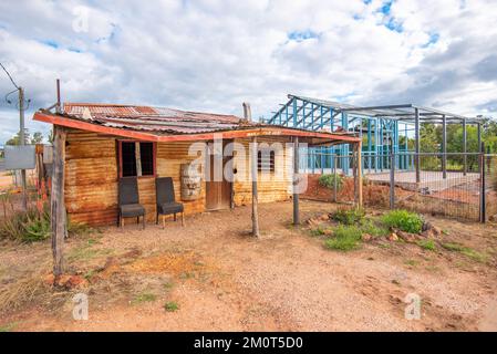 Ancien et nouveau, le cottage 1916 Coopers en rafle ondulé est situé à côté du cadre en acier d'un nouveau bâtiment en cours de construction dans la ville de Lightning Ridge Banque D'Images