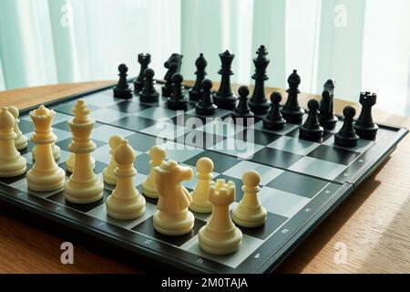 Jeu d'échecs sur la table en bois prêt pour le jeu dans la chambre près de la fenêtre. Concept de jeux intellectuels et d'activités de loisirs Banque D'Images