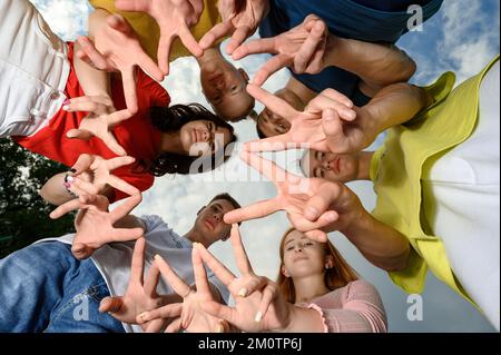 Ivano-Frankivsk, Ukraine, 14 juillet 2022: Les enfants heureux ont fait un cercle avec leurs têtes et leurs doigts, couleurs vives des vêtements pour enfants. Banque D'Images
