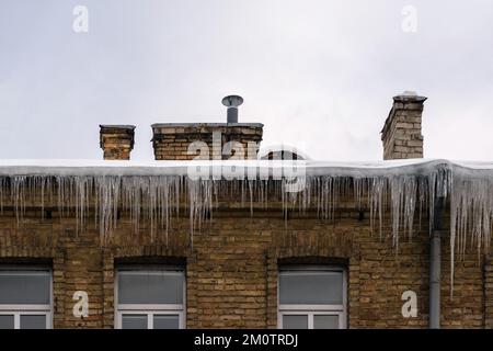 Glaçons pointus suspendus sur le bord du toit. La fonte de la neige forme de la glace. Banque D'Images