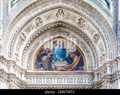 Gros plan sur la façade de l'église en marbre Santa Maria del Fiore ou de la cathédrale de Florence dans un style néo-gothique avec statues, niche et lunette ornée de fresques Banque D'Images