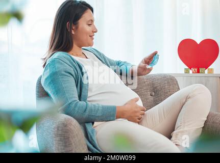 Femme enceinte, échographie et mère sur le canapé à la maison regardant l'image. Grossesse, sonographie et femme heureuse en maison avec photographie, sonogramme Banque D'Images