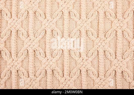 Arrière-plan beige tricoté. Grand tissu tricoté avec un motif. Gros plan d'une couverture tricotée. Décoration horizontale. Banque D'Images