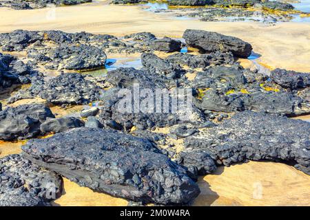 Côte volcanique des Rocheuses . Plage de sable avec formations de roches de lave Banque D'Images