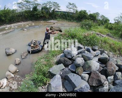 Les coolies traditionnelles prennent des pierres de la rivière pendant la journée pour les vendre comme matériaux de construction Banque D'Images