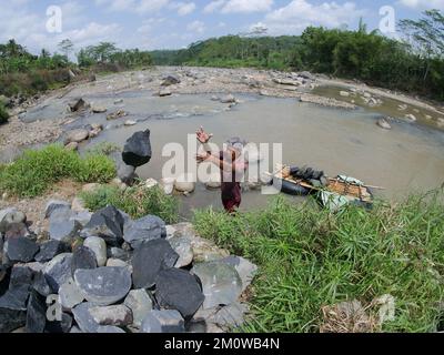 Les coolies traditionnelles prennent des pierres de la rivière pendant la journée pour les vendre comme matériaux de construction Banque D'Images