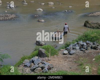 Les coolies traditionnelles prennent des pierres de la rivière pendant la journée pour les vendre comme matériaux de construction Banque D'Images