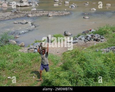 Les coolies traditionnelles prennent des pierres de la rivière pendant la journée pour les vendre comme matériaux de construction Banque D'Images