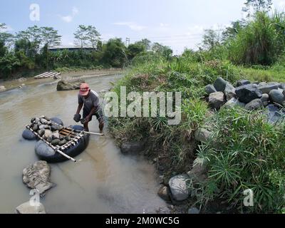 Les coolies traditionnelles prennent des pierres de la rivière pendant la journée pour les vendre comme matériaux de construction Banque D'Images