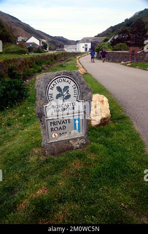 Couple à pied près de la confiance nationale panneau pour Boscastle par la rivière Valency sur le South West Coastal Path à Cornwall, Angleterre, Royaume-Uni. Banque D'Images