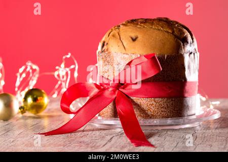 Gâteau aux fruits et au chocolat servi sur une table en bois décorée pour Noël. Pain de Noël fait maison sur fond rouge, espace copie. Banque D'Images