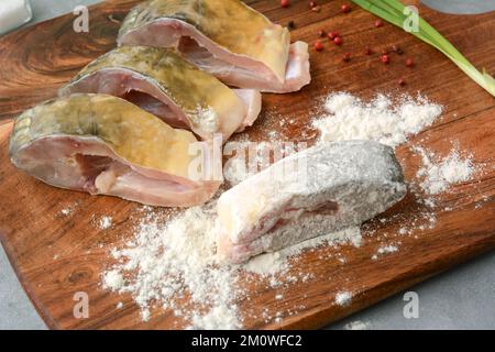 Tranches de carpe fraîches et crues panées dans de la farine. Préparation du poisson pour la friture. Plat de Noël polonais traditionnel Banque D'Images