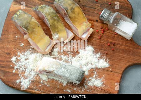 Tranches de carpe fraîches et crues panées dans de la farine. Préparation du poisson pour la friture. Plat de Noël polonais traditionnel Banque D'Images