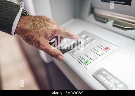 Gros plan d'un professionnel de la santé qui saisit le code PIN dans un distributeur automatique de billets. Image rognée d'un homme d'affaires en appuyant sur les boutons du clavier. Il retire de l'argent par u Banque D'Images