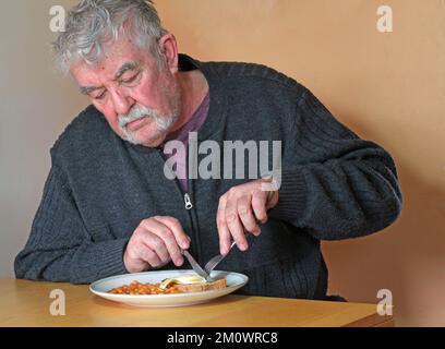 Homme âgé ou âgé assis seul et mangeant sa nourriture. dîner seul. Banque D'Images