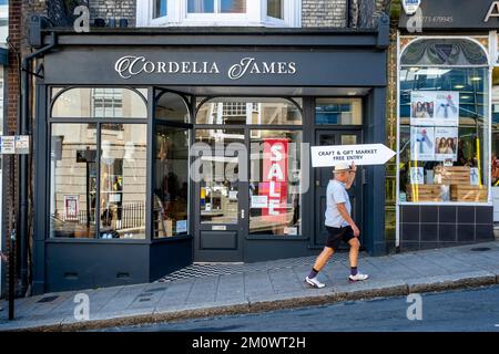Un homme monte sur Lewes High Street avec un panneau publicitaire, Lewes, East Sussex, Royaume-Uni. Banque D'Images