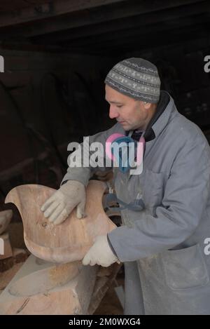 l'artisan sculpte les assiettes en bois à la main. L'art du menuisier Banque D'Images