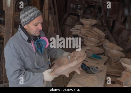 l'artisan sculpte les assiettes en bois à la main. L'art du menuisier Banque D'Images