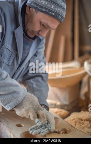 l'artisan sculpte les assiettes en bois à la main. L'art du menuisier Banque D'Images