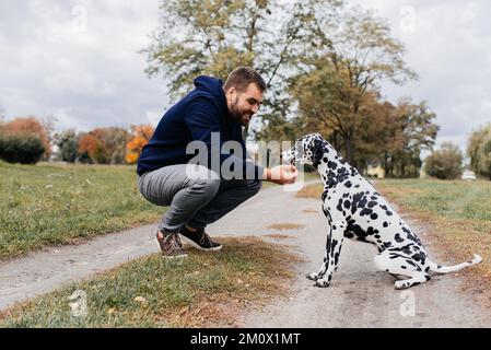 Image rognée d'un beau jeune homme avec labrador en plein air. Un homme sur l'herbe verte avec un chien. Cynologue Banque D'Images