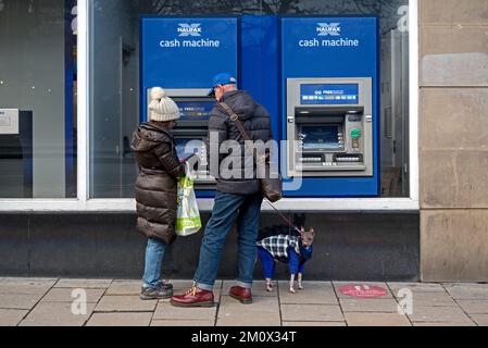 Couple avec un chien portant un manteau dans une caisse de la Halifax Bank à Princes Street, Édimbourg, Écosse, Royaume-Uni. Banque D'Images