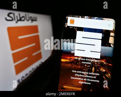 Personne tenant un smartphone avec une page web de la société pétrolière et gazière algérienne Sonatrach à l'écran devant le logo. Concentrez-vous sur le centre de l'écran du téléphone. Banque D'Images