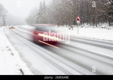 Deux voitures roulant sur une route enneigée, flou de mouvement, signal d'avertissement en descente, Hesse, Allemagne, Europe Banque D'Images