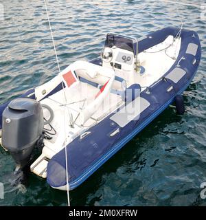 Bateau gonflable moderne avec moteur dans la mer près de la rive, bateau gonflable bleu blanc Banque D'Images