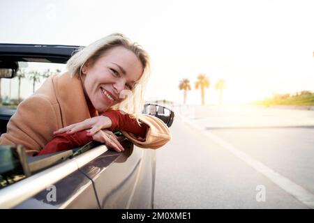 Blanche blonde d'âge moyen femme dans une voiture regardant la caméra Banque D'Images