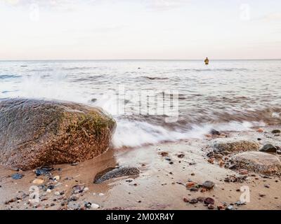 Le pêcheur reste dans l'eau et tire l'appât sur sa canne à pêche. Côte Baltique, Allemagne Banque D'Images