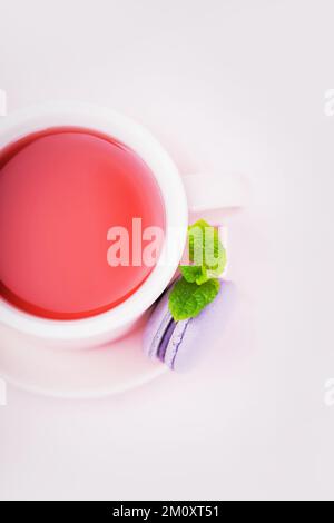 Thé aux fruits, macaron blackberry avec feuille de menthe sur fond rose, espace de copie Banque D'Images
