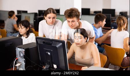 Portrait d'un groupe multinational de jeunes étudiants réagissant émotionnellement tout en étudiant à un pc en classe informatique Banque D'Images