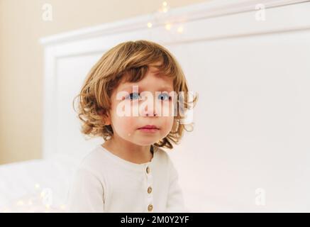 Portrait de la petite fille tearful.petite fille mignonne est crying.indoor.curly cheveux et yeux bleus. Banque D'Images