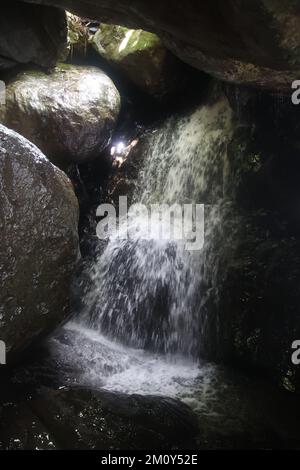 une grande cascade à côté d'un rocher dans l'ombre Banque D'Images