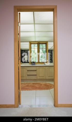 Vanité de salle de bains à travers l'embrasure de porte à l'intérieur d'une maison de style architectural et décoré mélangé. Banque D'Images