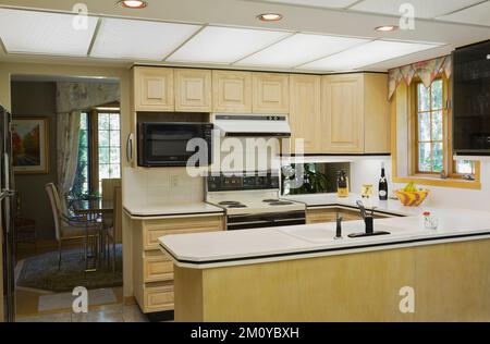 Armoires en bois jaunâtre brun blanchi dans la cuisine à l'intérieur de la maison de style décoré et architectural mélangé. Banque D'Images