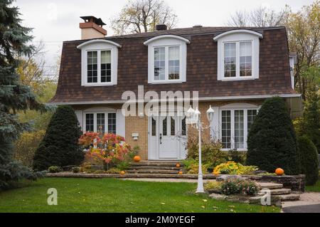 Brique beige avec garniture blanche maison de style cottage avec deux tons brun bardeaux d'asphalte toit en automne. Banque D'Images