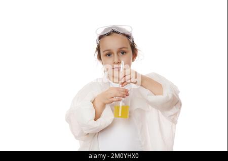 Élève de l'école primaire, petite fille en blouse de laboratoire, à l'aide d'un bâton de verre de laboratoire, mélange la solution chimique jaune dans un bécher, Banque D'Images
