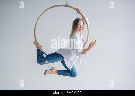 Gymnaste caucasien de sexe féminin faisant des exercices de canulars aériens et en utilisant un smartphone. Banque D'Images