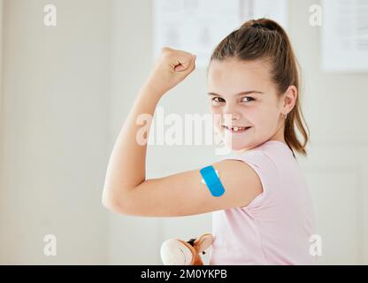 Im super protégé. une petite fille avec un bandaid sur son bras à un bureau de médecins. Banque D'Images