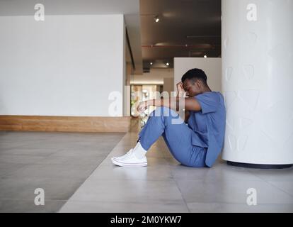 Offrez-vous la pause dont vous avez besoin. un jeune médecin de sexe masculin a l'air fatigué alors qu'il travaillait dans un hôpital moderne. Banque D'Images